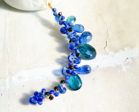 This pendant brings together a magical blend of indigo blue and teal blue kyanite in a beautiful crescent shape. It is wire wrapped with several type of blue gemstones, ready to dress up any look. 